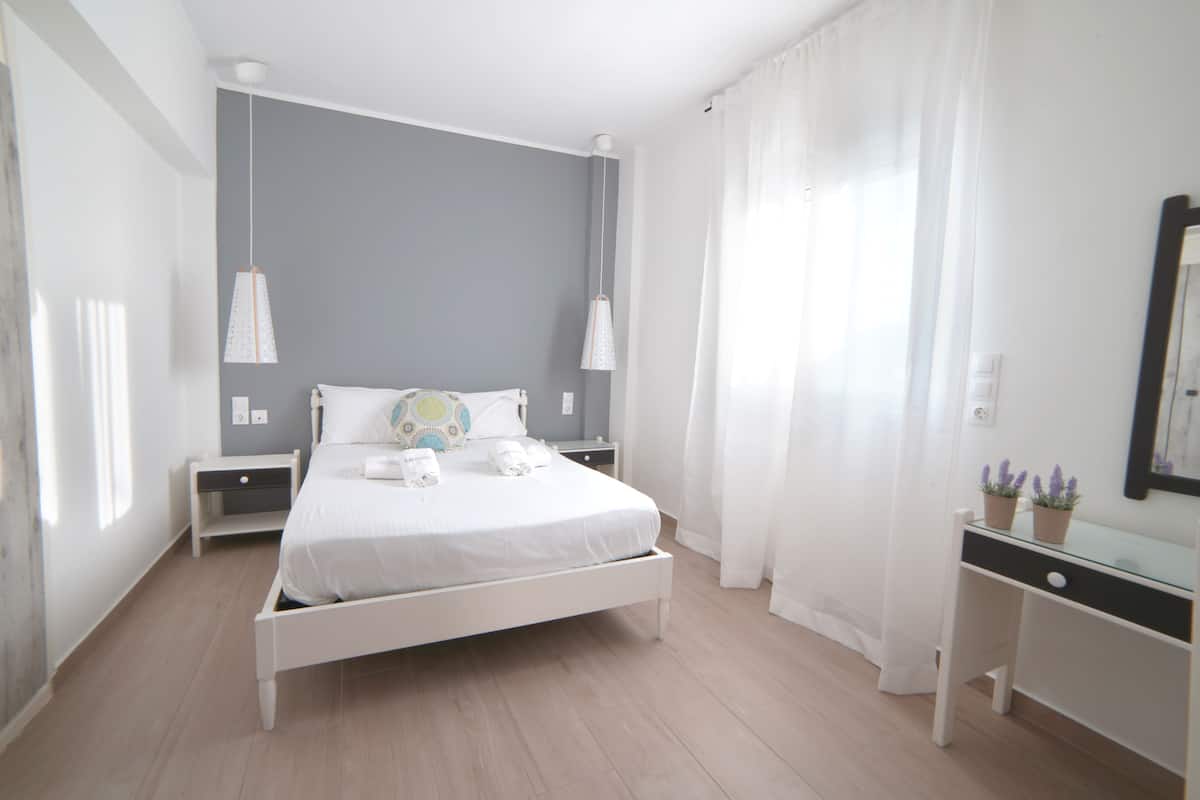 A modern bedroom with a bed, bedside tables, a desk, and a mirror.