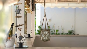 Un espace bar doté d’un comptoir en marbre, de décorations suspendues et offrant une vue sur l’extérieur.