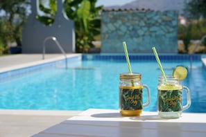 Two mason jars with straws and a lime slice, labeled "Good vibes only," on a poolside table. - Mirsini Studios & Apartments (Zakynthos)