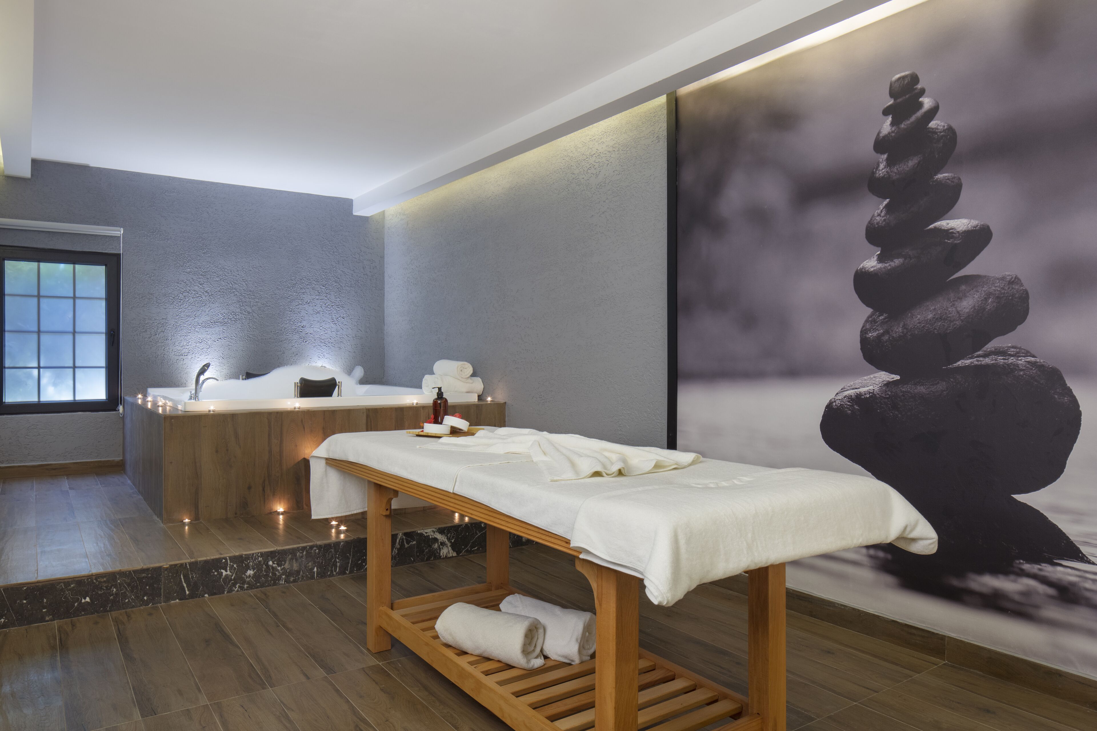 Un spa moderno con un banco de madera, una gran escultura de piedra, una bañera y un lavabo.