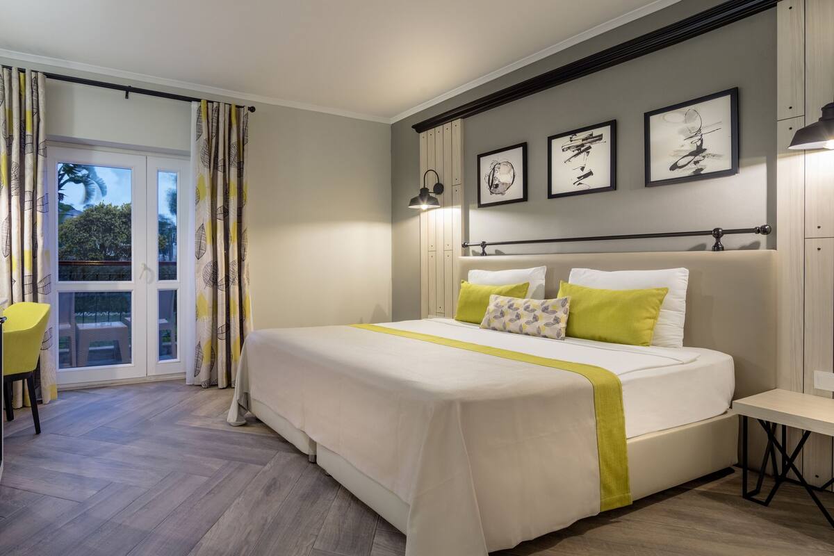 A bedroom with a bed, bedside tables, a desk, and a window with curtains.