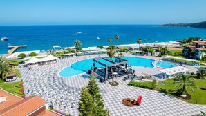 Un complejo turístico con varias piscinas, un escenario techado y vistas al mar.