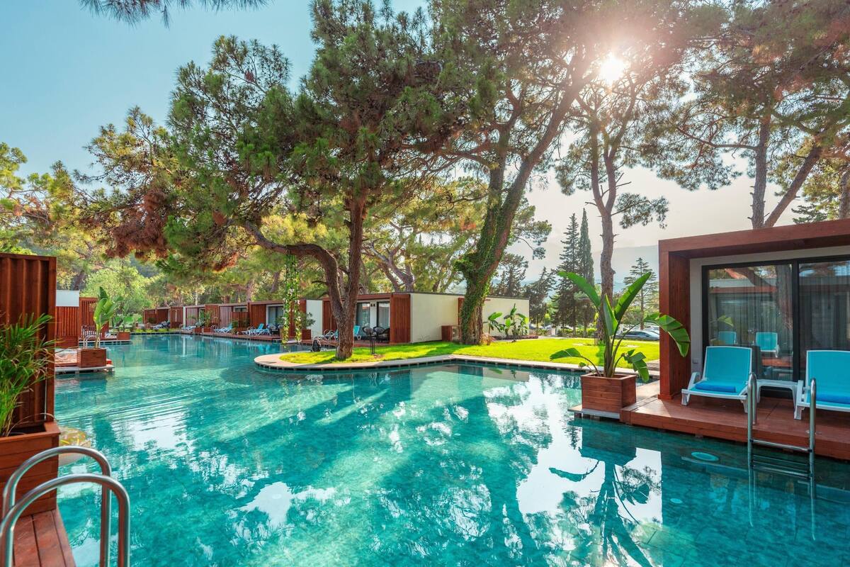 A pool area with clear water, surrounded by trees and wooden structures.