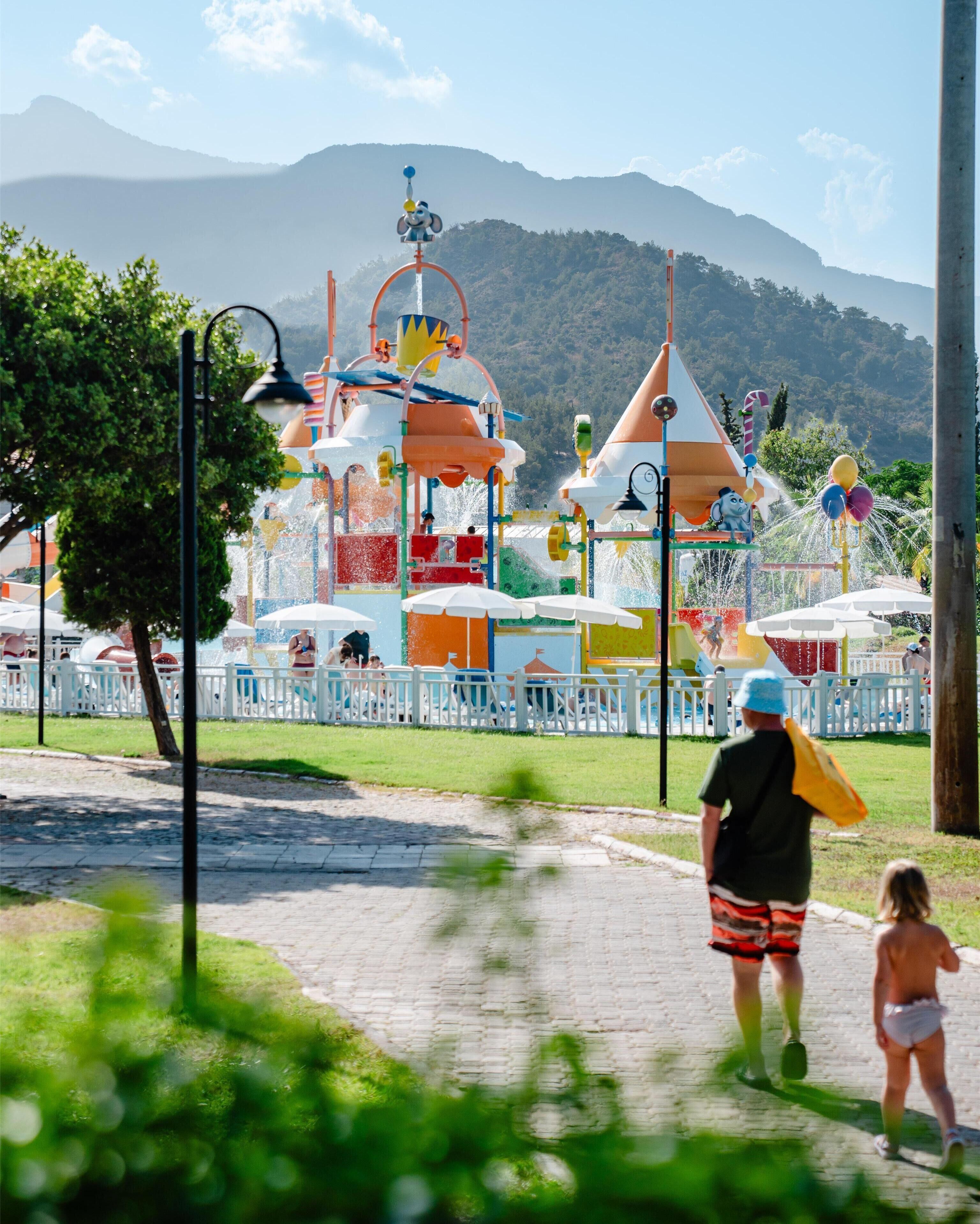 Un parque acuático con coloridas estructuras de juego y un paisaje montañoso.