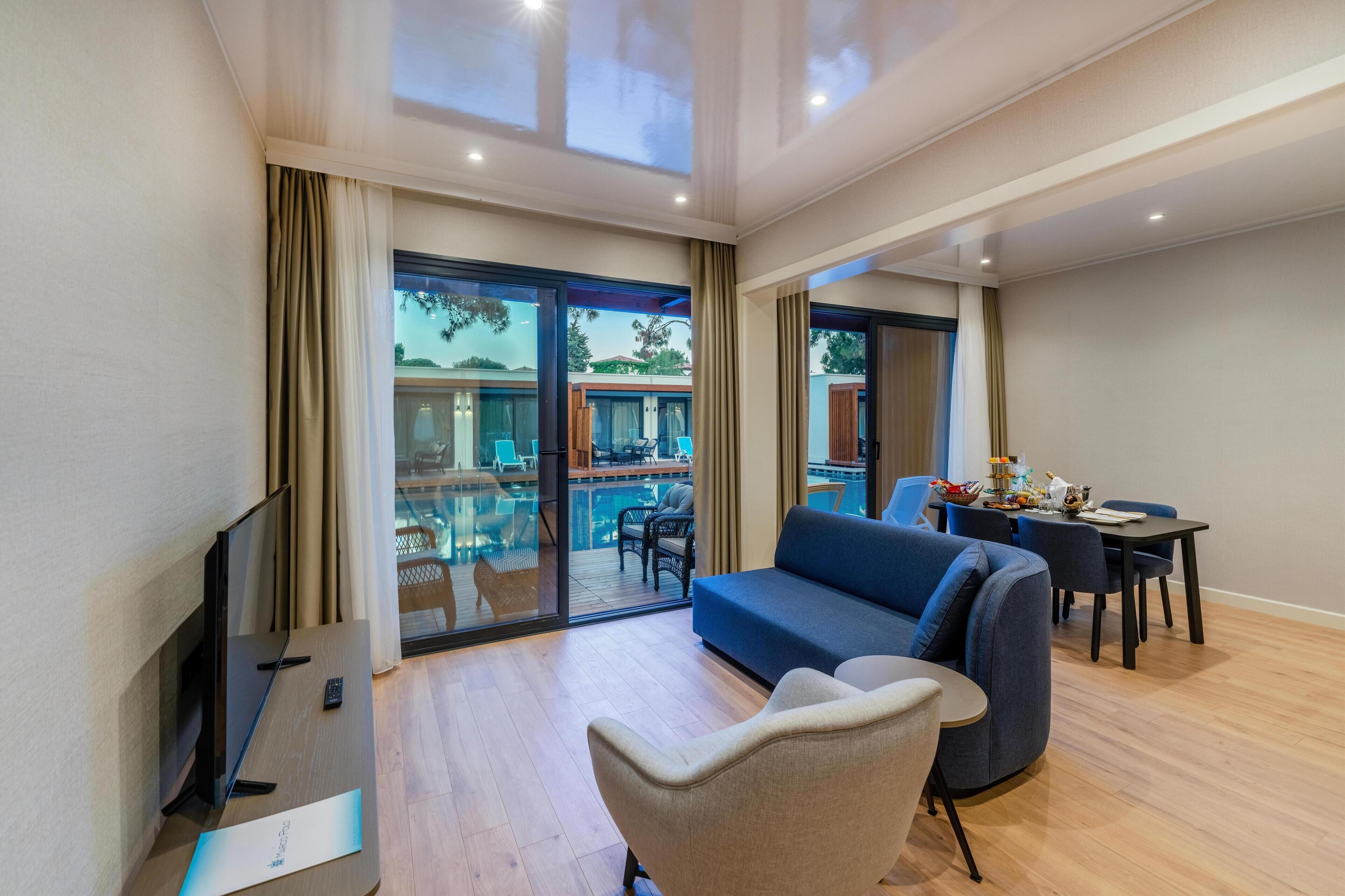 Una sala de estar moderna con un sofá, sillas, un televisor y una mesa de comedor.