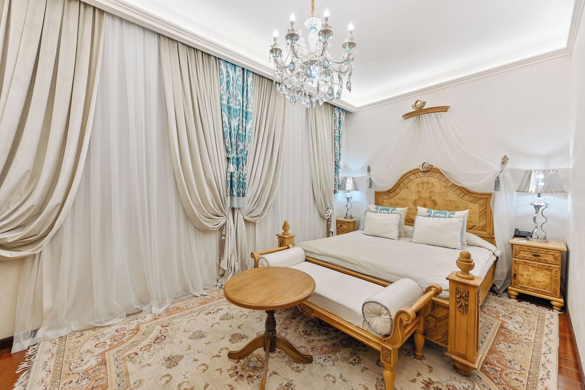 A bedroom with a large bed, a chandelier, a bedside table, and a nightstand.