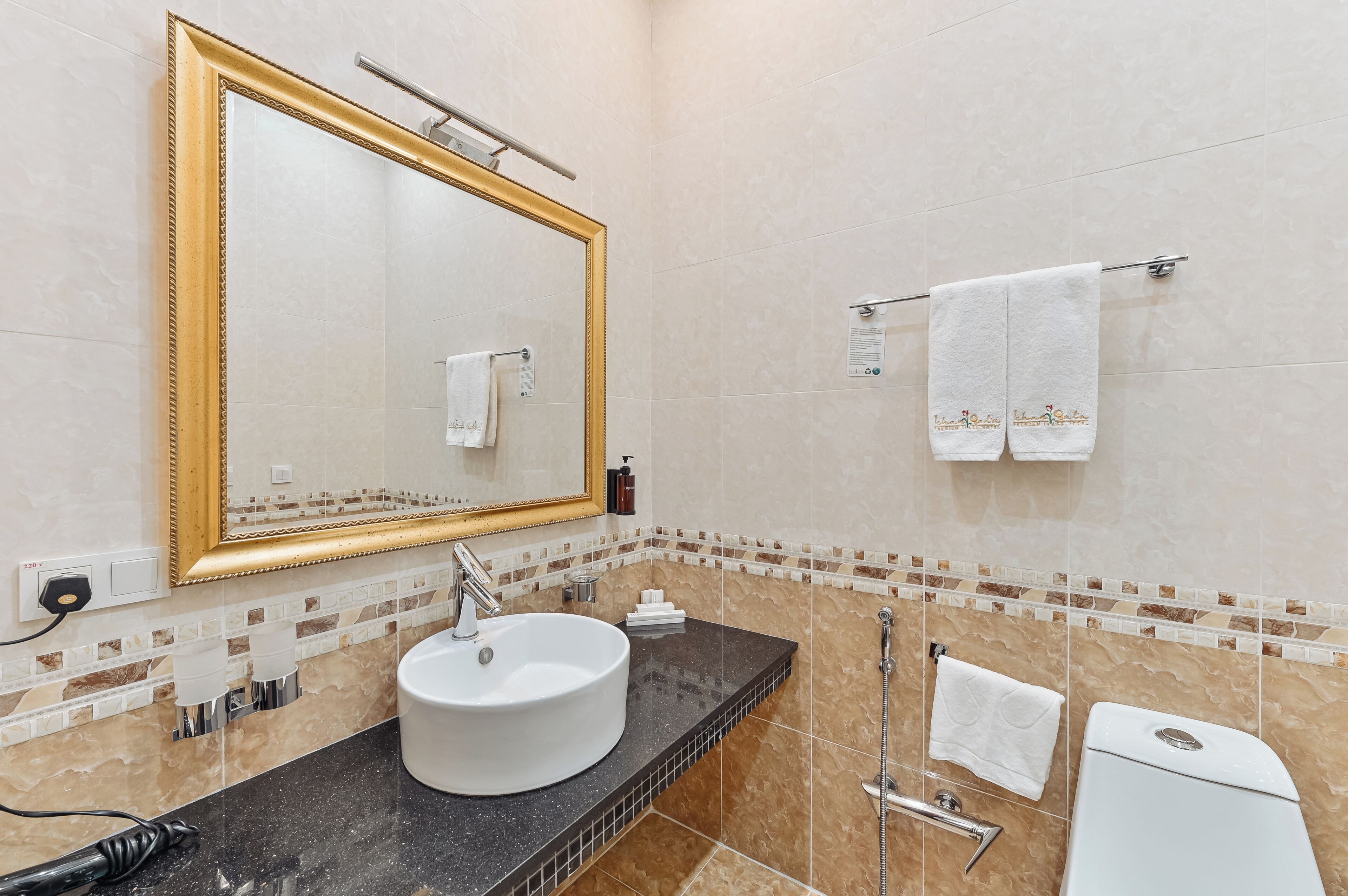 A bathroom with a large mirror, a sink, a toilet, and a shower.