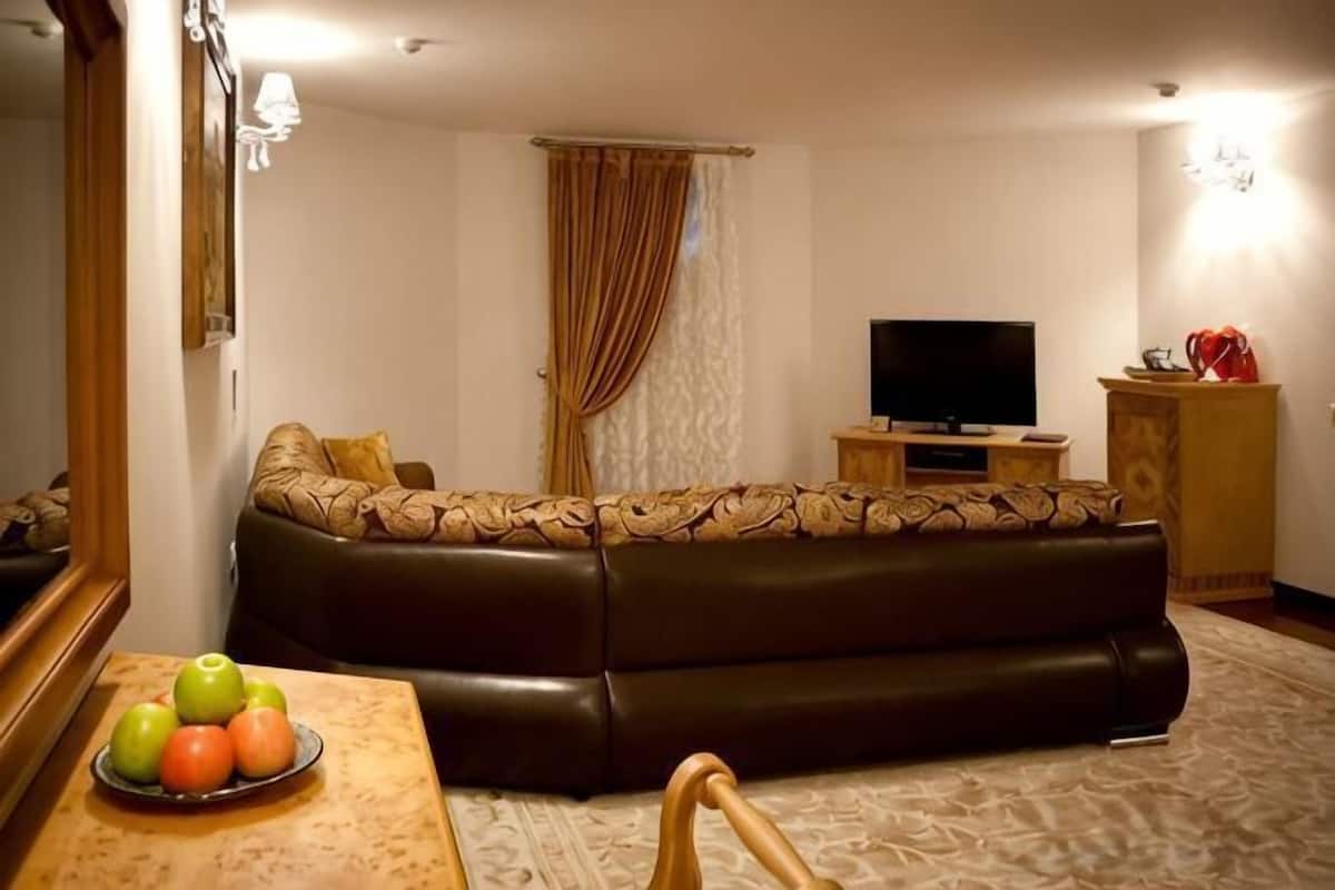 A living room with a brown leather sofa, a television, and a small wooden cabinet.