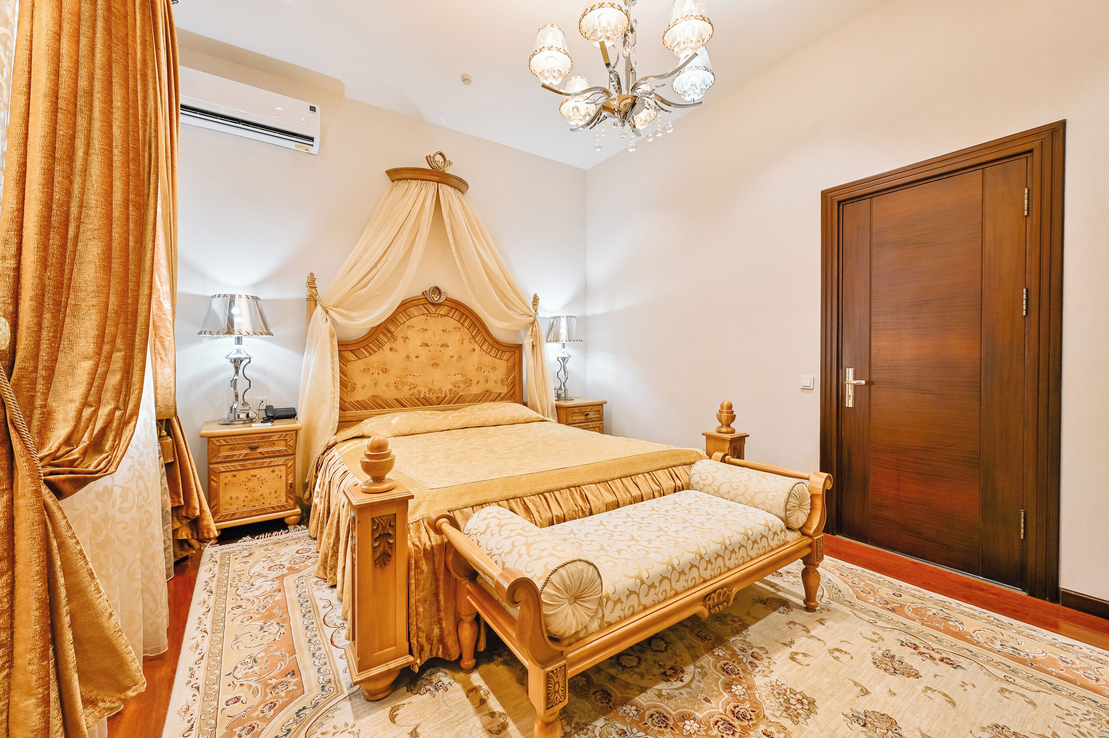 A bedroom with a four-poster bed, a wooden wardrobe, and a chandelier.