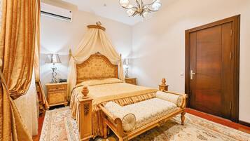 A bedroom with a four-poster bed, a wooden wardrobe, and a chandelier.
