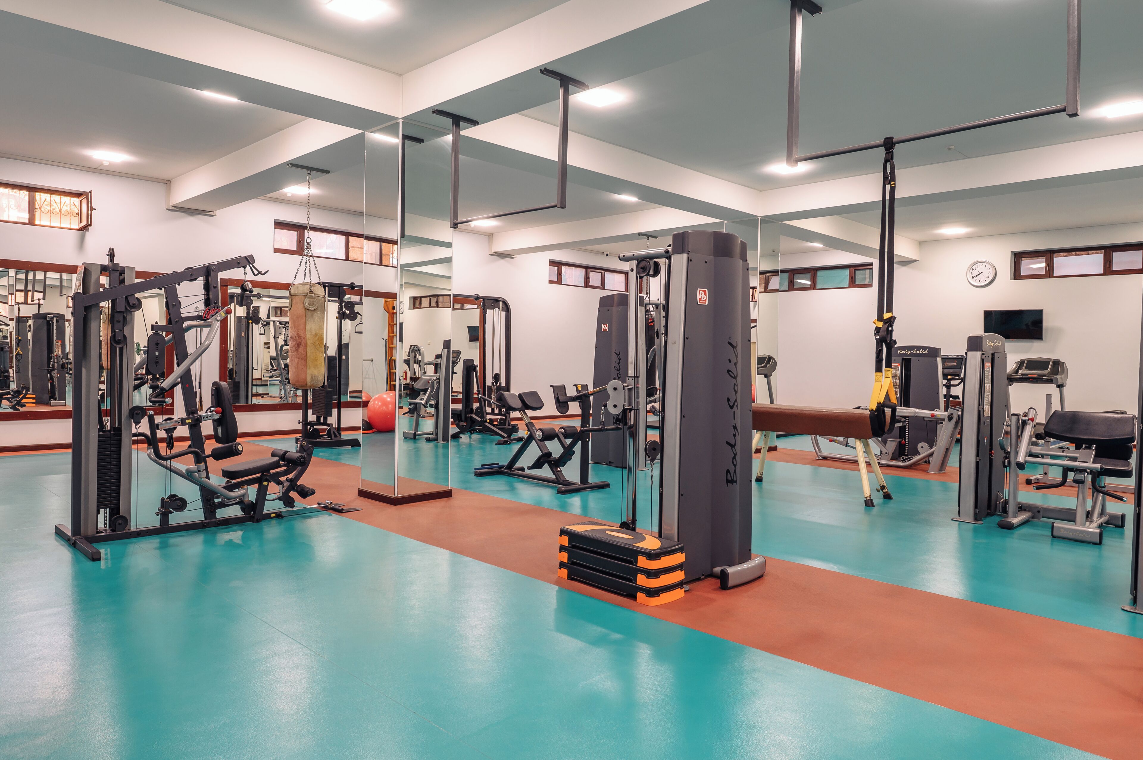 A gym with various exercise machines, a bench, and a punching bag.