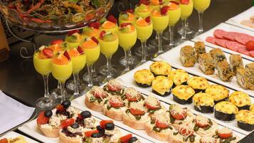 A buffet with various food items including fruit cups, sushi, and appetizers.