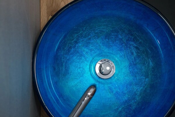 A blue circular object with a central metallic part and a metallic rod extending from it.