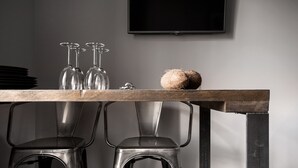 A dining table with four wine glasses and a coconut on it, flanked by two metal chairs.