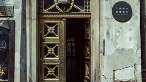 A building entrance with a large ornate door, a sign for "GOOD APARTMENTS," and a security camera.
