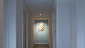 A narrow hallway with a light blue door at the end, flanked by white walls and a light-colored floor. - Hotel Casablanca (Rimini)