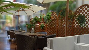 An outdoor seating area with wicker furniture, a table with a lantern, and a wooden lattice backdrop with greenery. - Hotel Casablanca (Rimini)