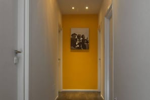 A hallway with a yellow wall and a framed picture.