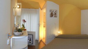A hotel room with a bed, a desk with a mirror, a small table with a plant, and a picture on the wall. - Hotel Casablanca (Rimini)