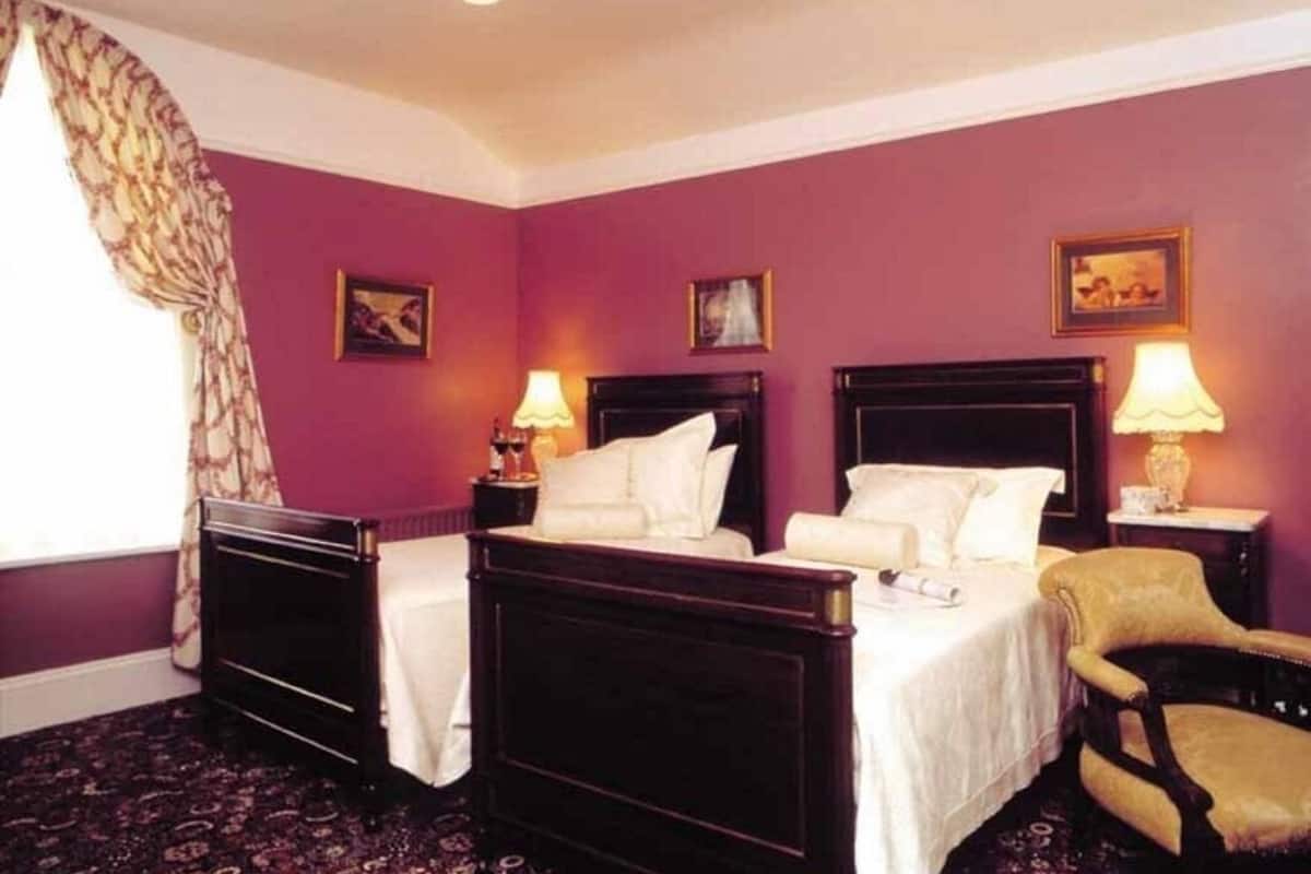 A room with two beds, a chair, and a nightstand with lamps.