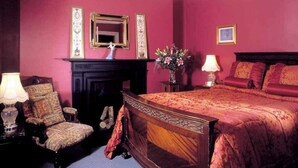 A bedroom with a large bed, a chair, a fireplace, and a mirror on the wall. - Ivyleigh House (Portlaoise)