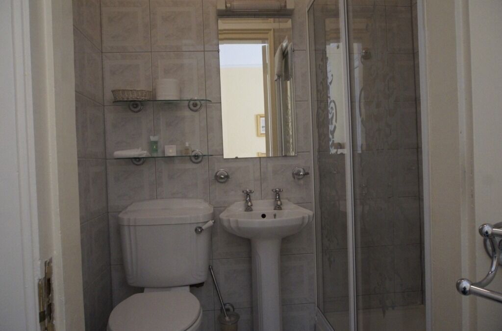 A compact bathroom with a toilet, sink, and a glass shower enclosure.