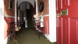 A hallway with a red door, a staircase, and a table with a lamp and a candle. - Ivyleigh House (Portlaoise)