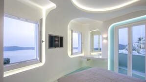 A modern bedroom with a large bed, a TV, and a view of the sea. - Andronikos Santorini (Santorini)
