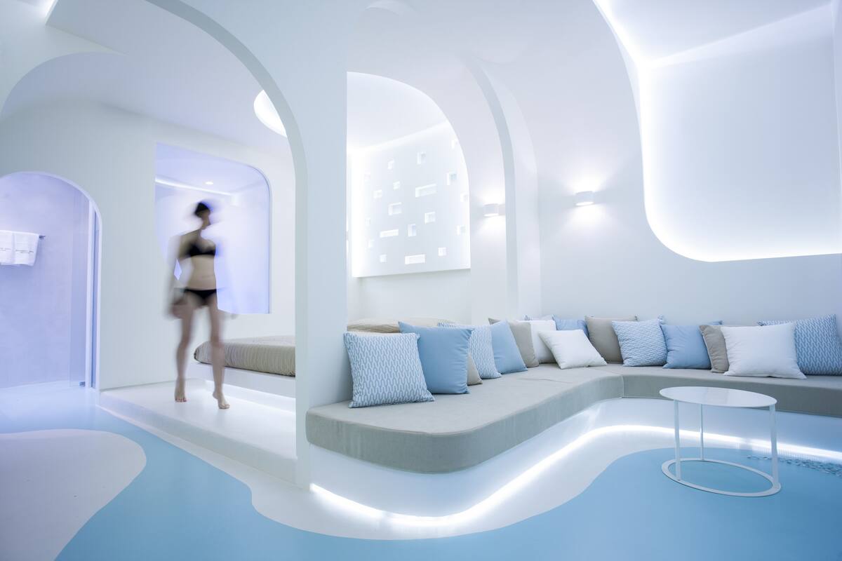 A modern interior with a curved seating area, a small table, and a person walking.