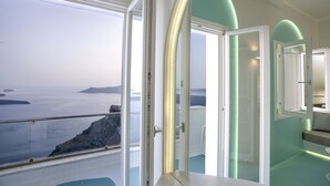 A modern room with a large window overlooking a coastal landscape. - Andronikos Santorini (Santorini)