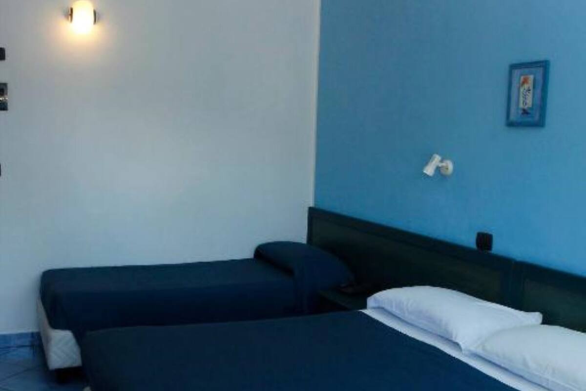 A room with two beds, a wall-mounted light, and a small picture frame.
