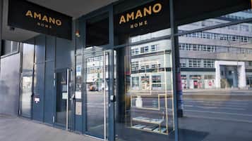 Un bâtiment moderne, avec une enseigne « AMANO HOME », de grandes portes vitrées et une vue sur la rue.
