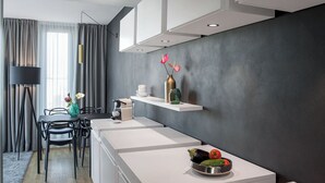 Una cocina moderna con armarios blancos, una zona de comedor con mesa y sillas, y una pared de acento oscura.