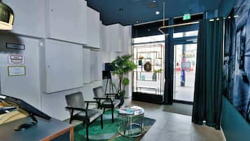 A reception area with a desk, chairs, a potted plant, and a view of the street outside.