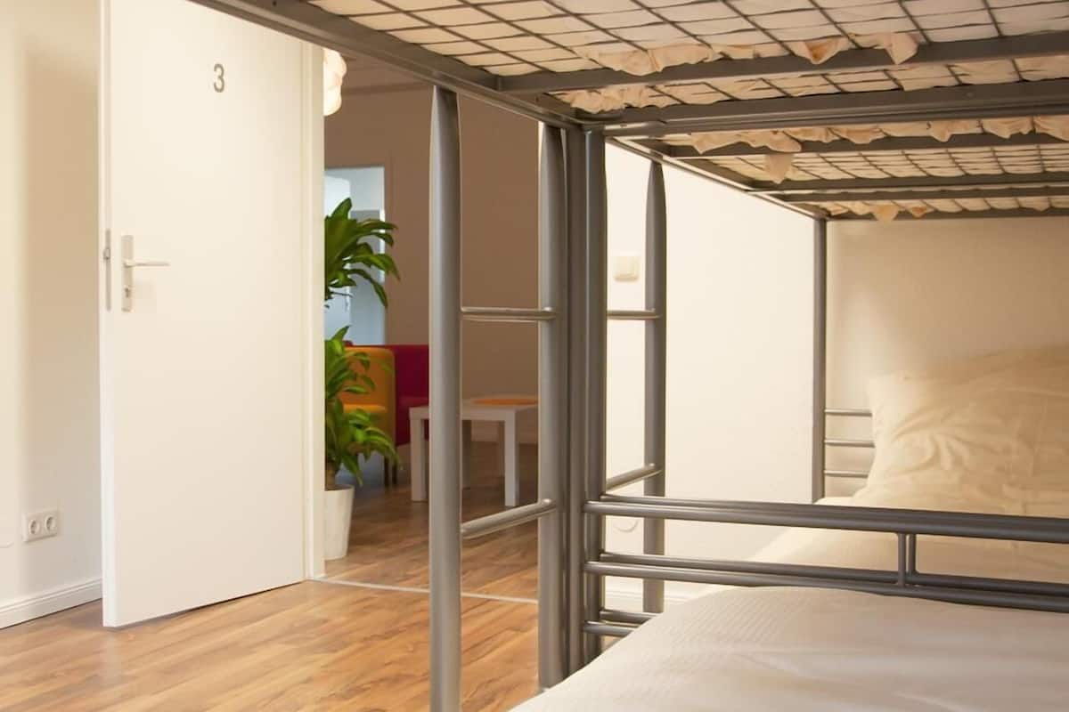 A room with a metal bed frame, a white door, and a wooden floor.