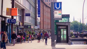 Eine belebte Stadtstraße mit einem U-Bahn-Eingang, verschiedenen Geschäften und Fußgängern.