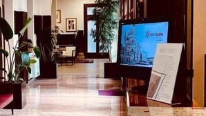 A hotel lobby with a reception desk, seating area, and a large screen displaying a cityscape. - Domus Ciliota (Venice)