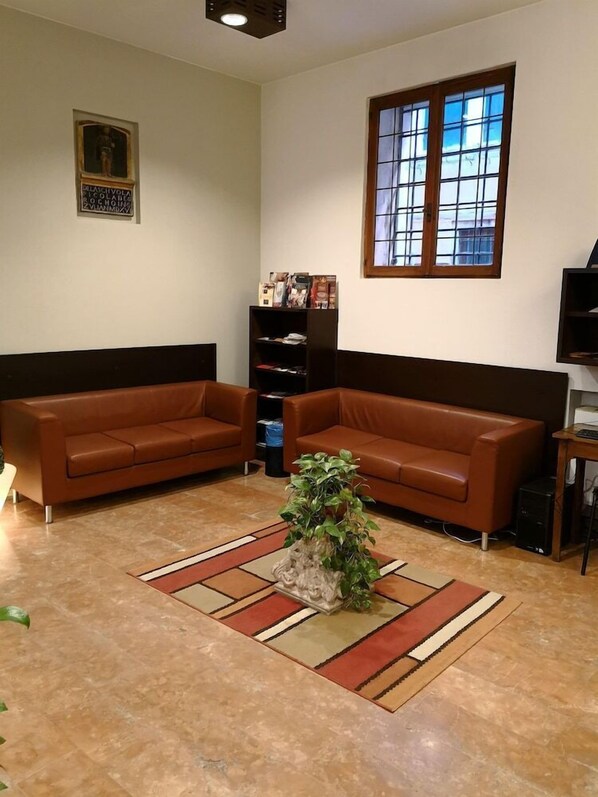 A living room with two brown sofas, a coffee table with a plant, a bookshelf, and a window with a view. - Domus Ciliota (Venice)