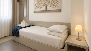 A hotel room with a bed, a nightstand, a wall-mounted lamp, a window with curtains, and a painting of a tree. - Domus Ciliota (Venice)