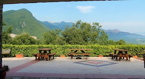 An outdoor seating area with picnic tables and potted plants, overlooking a mountainous landscape. - Le Coccole (Guardiaregia)