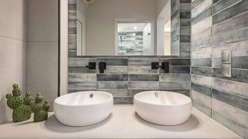 A bathroom with two white sinks, a mirror, and a tiled backsplash.
