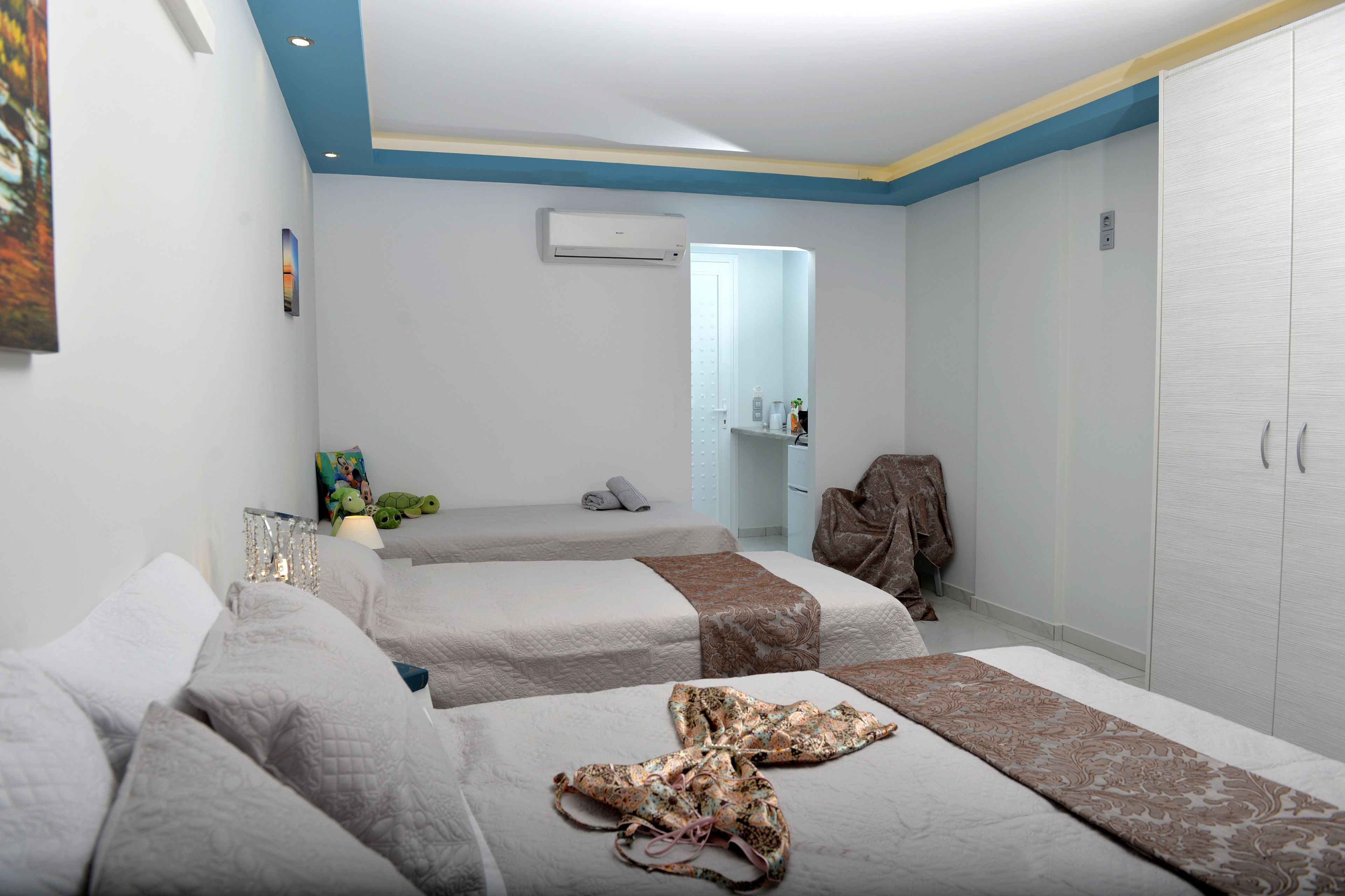 A hotel room with two beds, a wardrobe, a mirror, and an air conditioning unit.