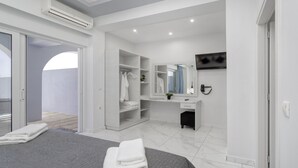 Un dormitorio moderno con cama, vestidor, tocador con espejo y televisor en la pared.