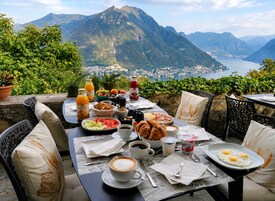 Mesa lista para el desayuno, con vistas a la montaña, que incluye una variedad de alimentos y bebidas.