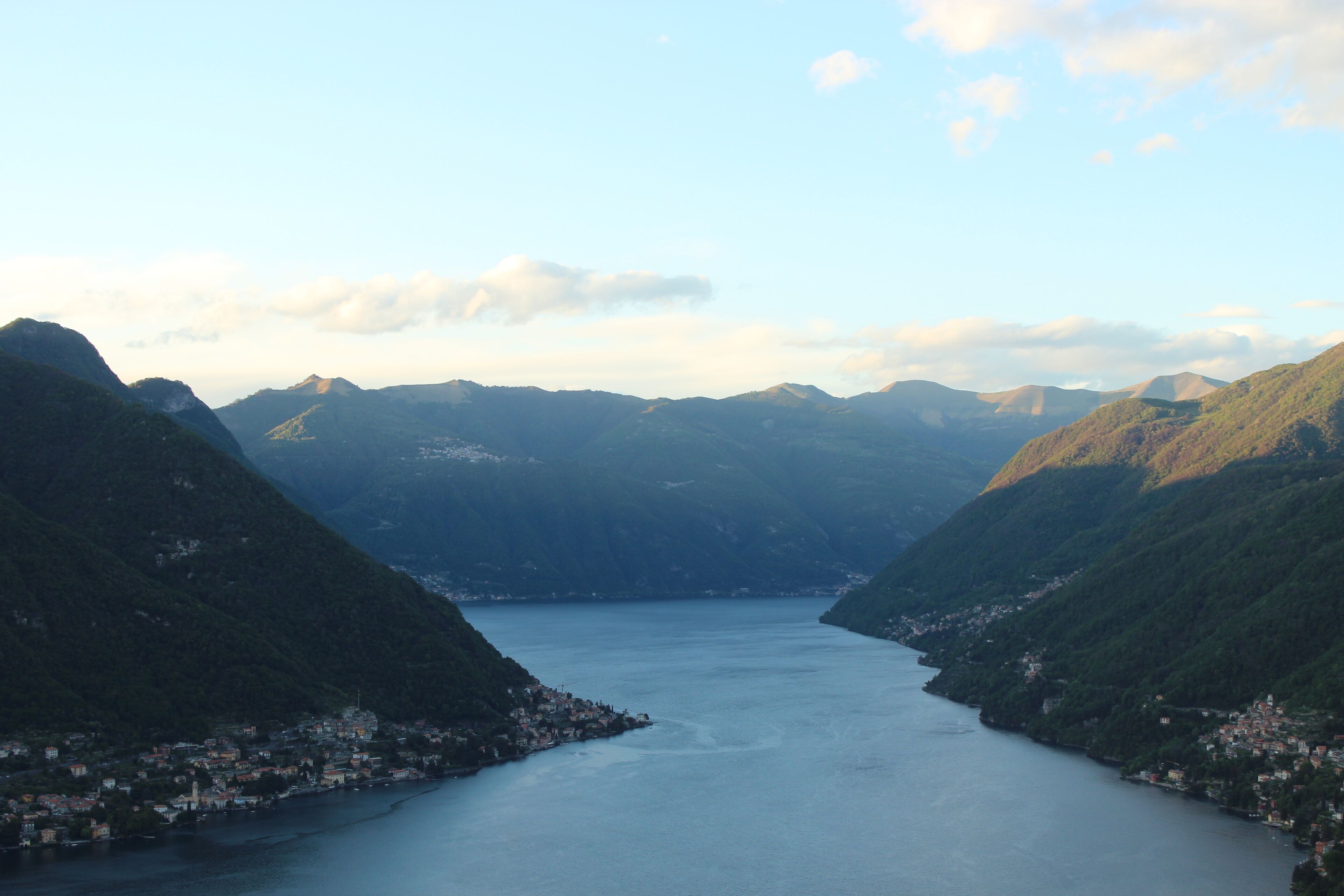 Ein Panoramablick auf einen See, umgeben von Bergen, mit einer Stadt, die sich entlang des Ufers anschmiegt.
