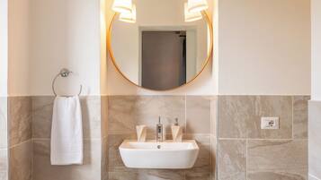 A bathroom with a white sink, two wall-mounted lights, and a towel hanging on a metal rack.