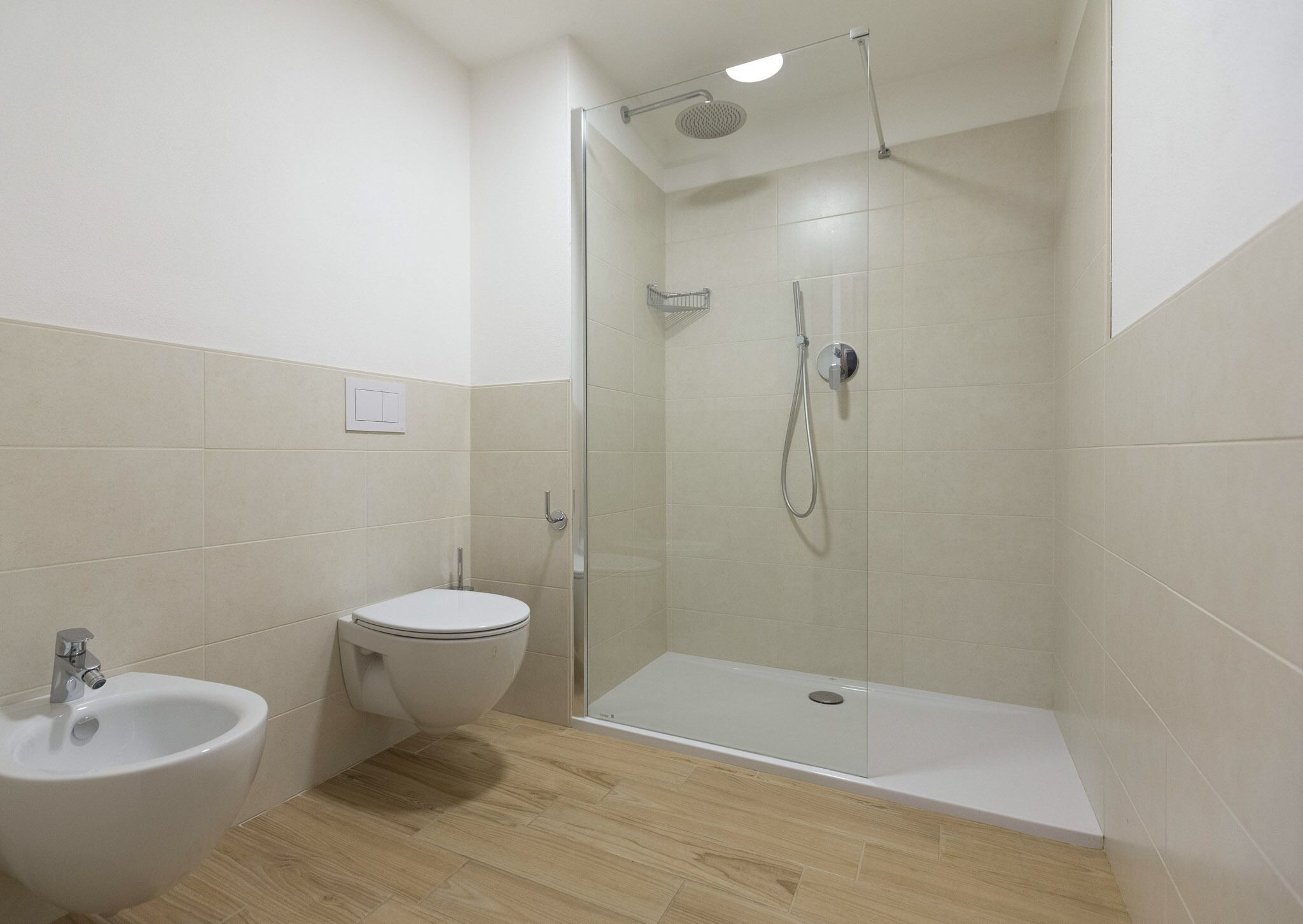 A modern bathroom with a toilet, bidet, and a glass-enclosed shower area.