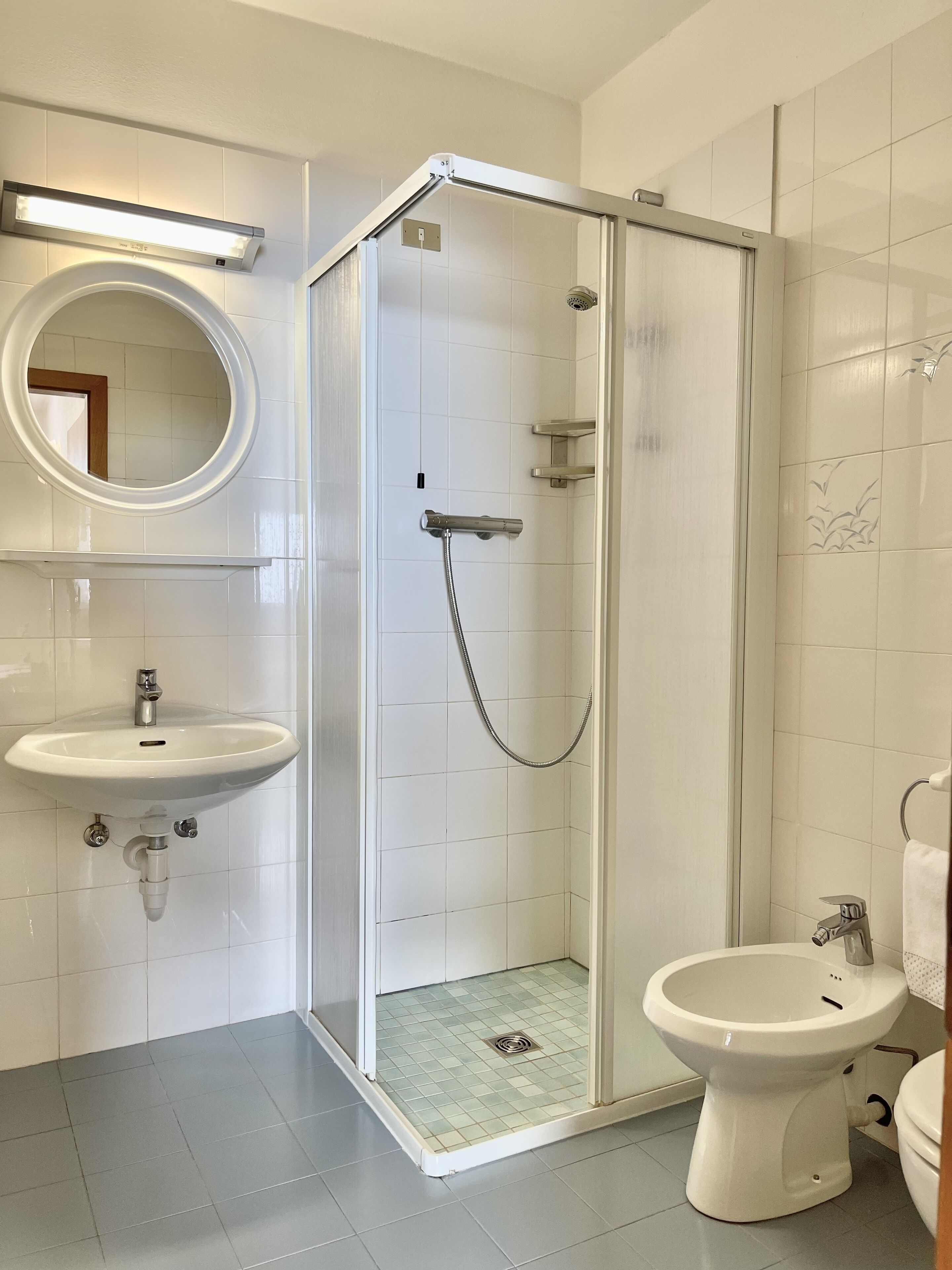 Et moderne badeværelse med bruseniche, et konsolbord med vask og et toilet.