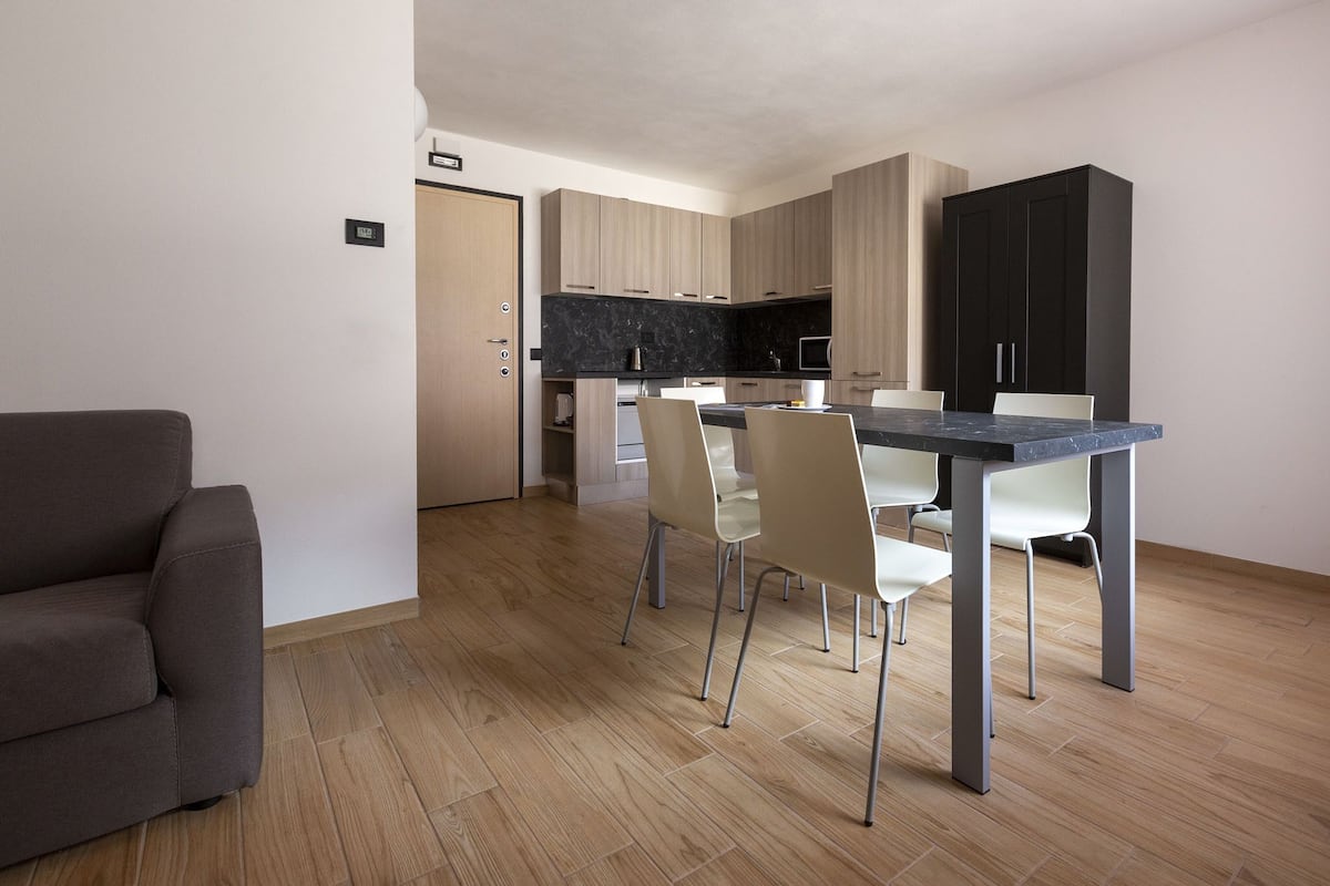 Une cuisine moderne avec un coin repas, un plancher en bois et un canapé gris.