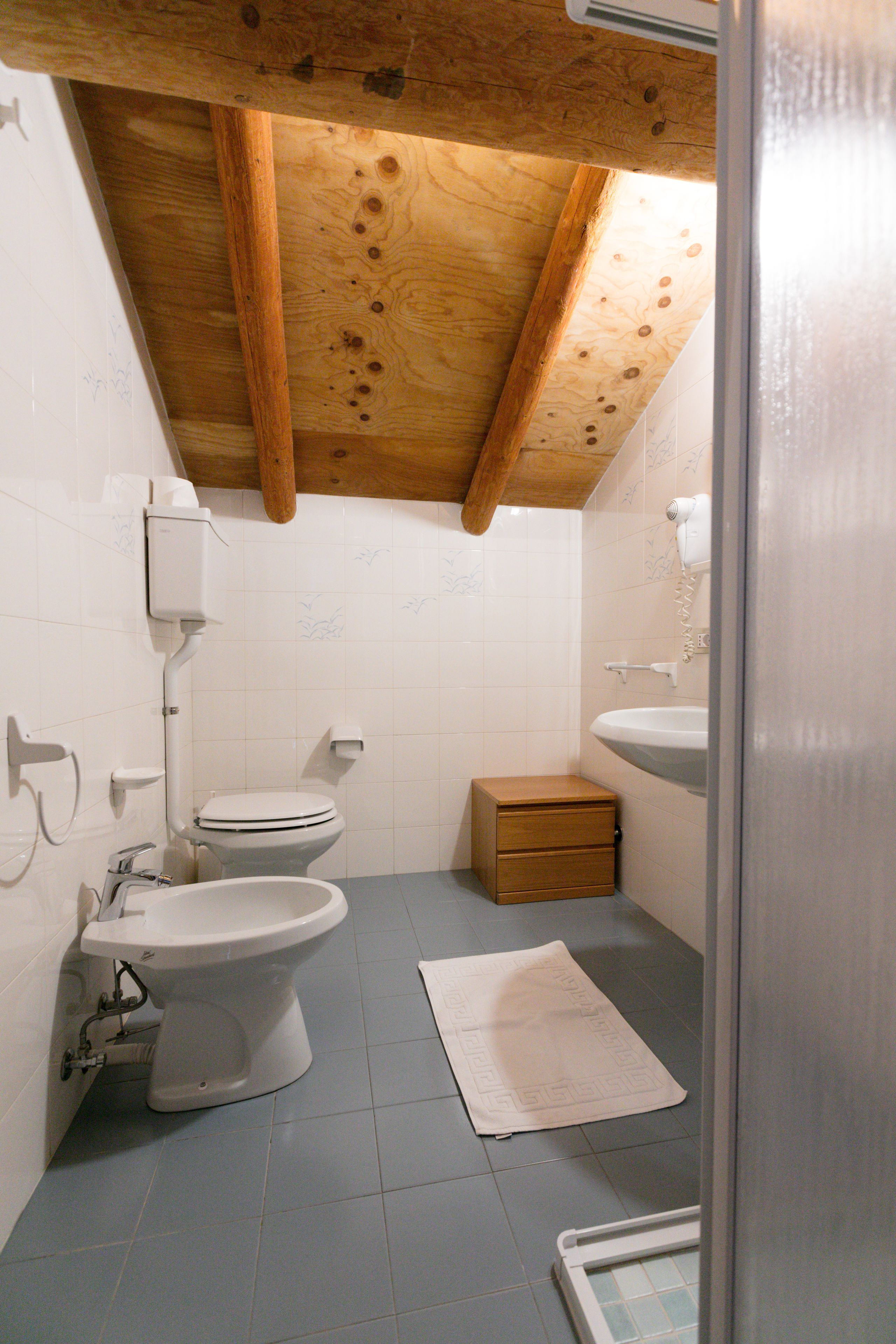A small, compact bathroom with a toilet, bidet, and sink.